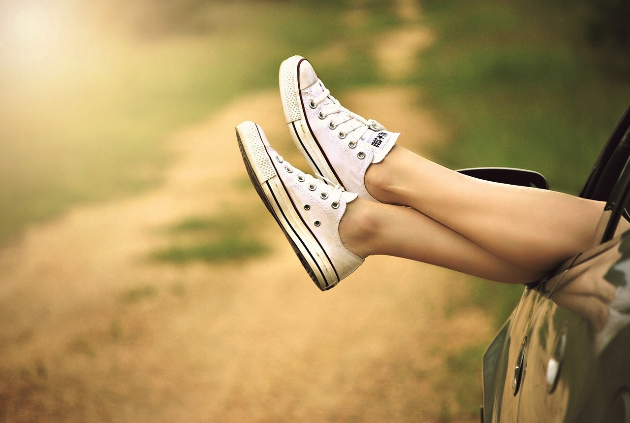 Legs droop out of a car window showing feet with canvas shoes. Image by lisa runnels from Pixabay